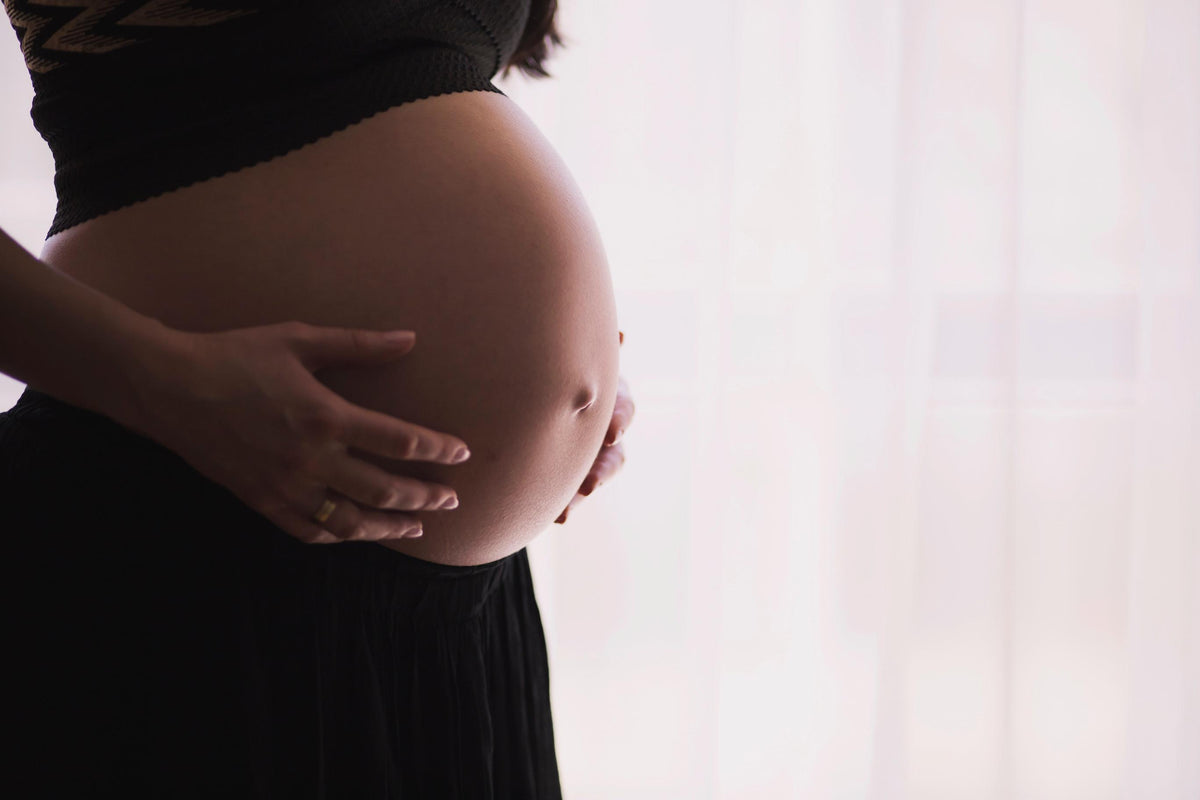 pregnant woman holding hands on stomach over baby bump