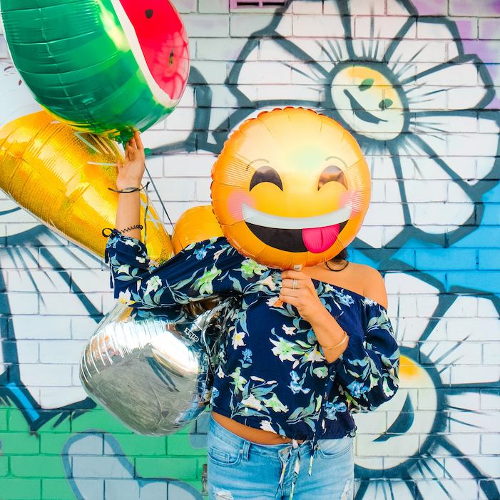 Woman holding balloons over her face, blushing